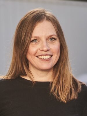 Portrett av smilende kvinne med langt, mellomblondt hår. Foto.