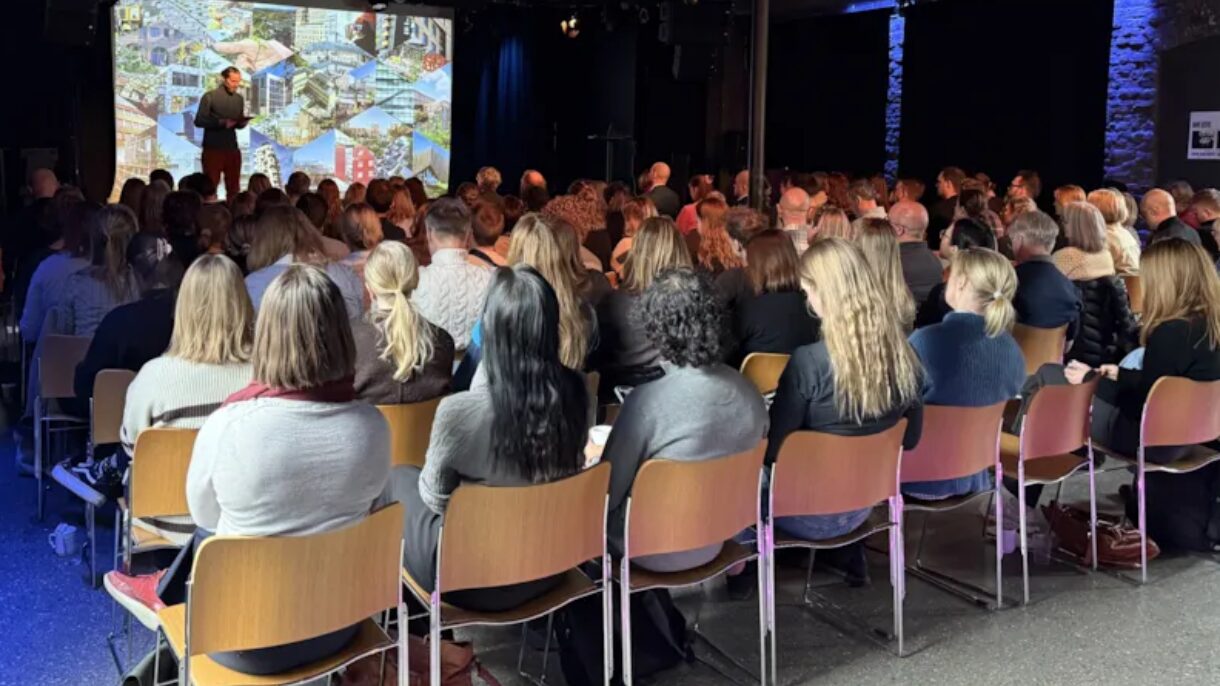 Mennesker sett bakfra sittende på stoler på seminar