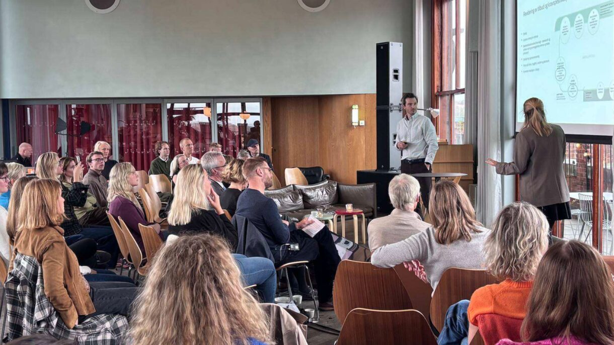 Mann og kvinne holder foredrag for publikum.