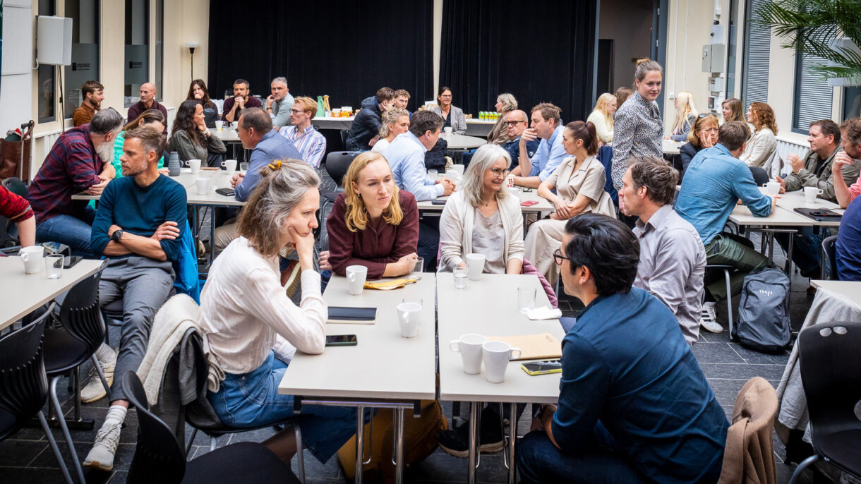 Mange personer som sitter ved et bord og deltar på seminar. Foto.