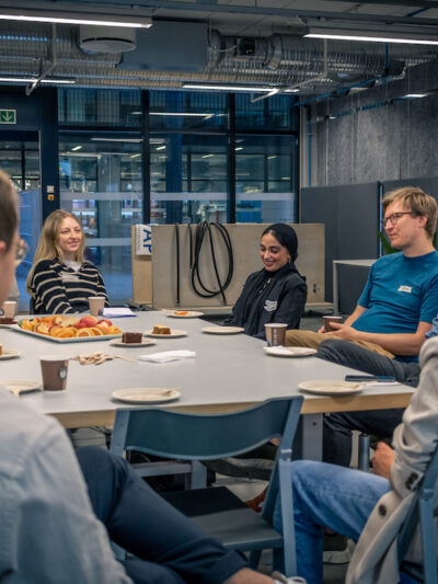 Sju personer sitter rundt et bord og snakker sammen