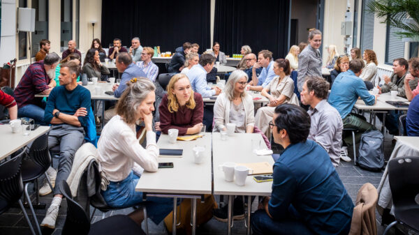 Mange personer som sitter ved et bord og deltar på seminar. Foto.