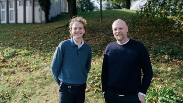 To smilende menn fotografert utendørs. Foto.