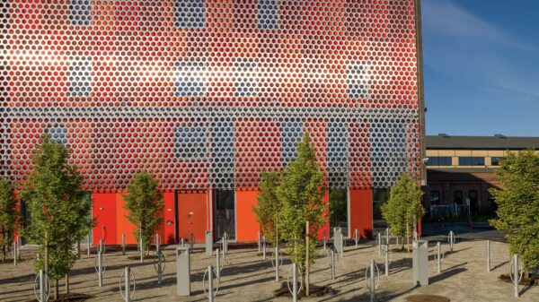 Kontorbygg. Rød fasade og trær. Foto.