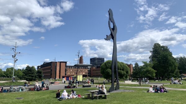 Park med plen, skulptur og folk.
