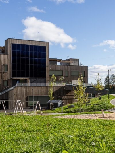 Skolebygg med solcellefasade. Gress i forkant. Foto.