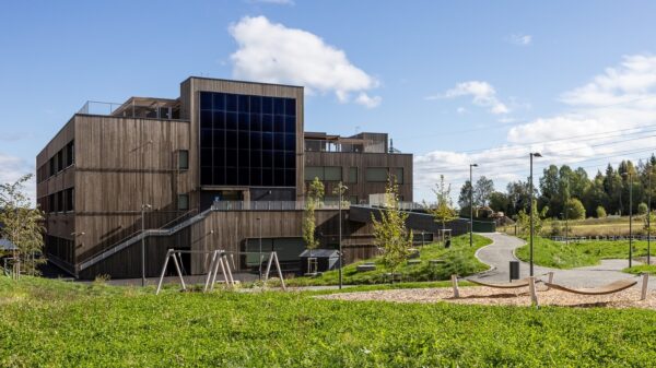 Skolebygg med solcellefasade. Gress i forkant. Foto.