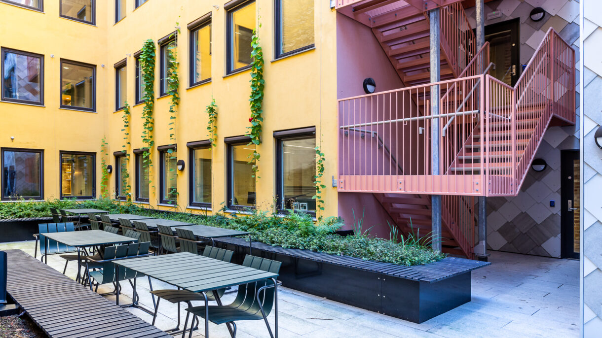 Takterrasse med møblering, opphøyde bed og gule fasader. Foto