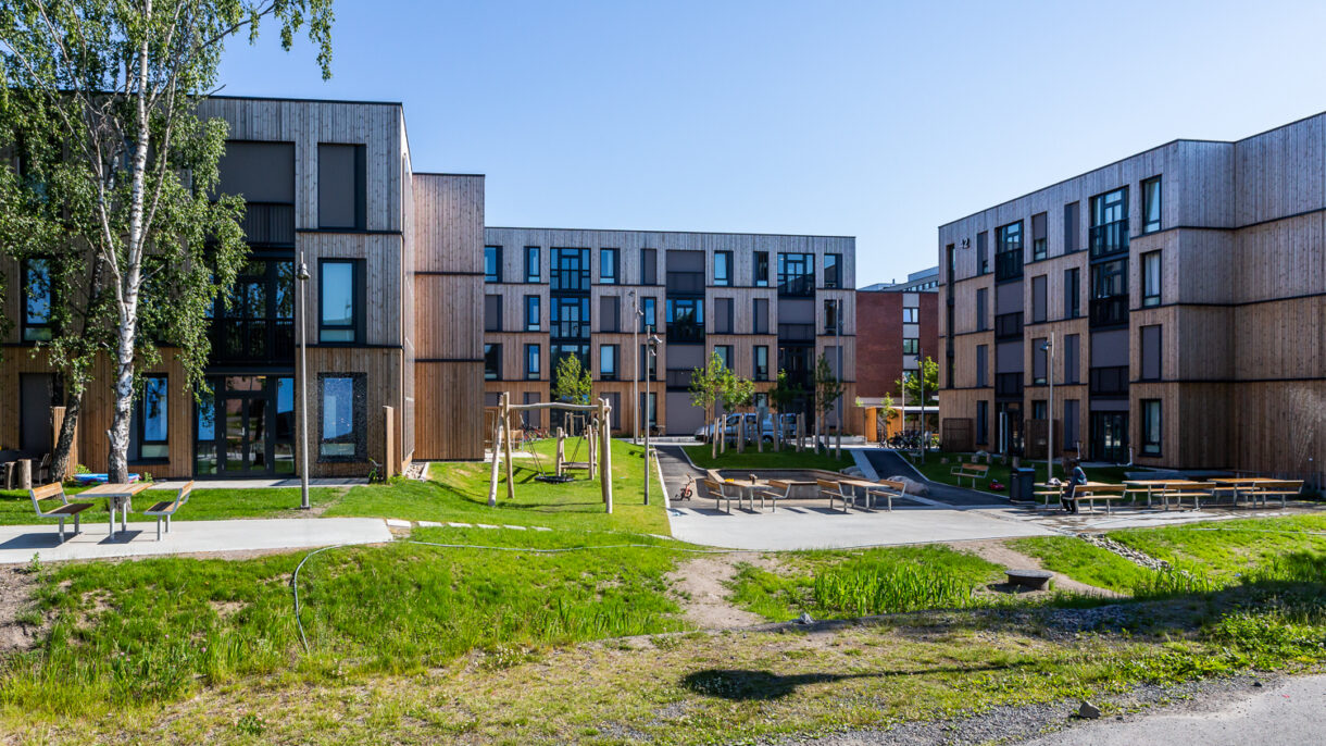 Studentboliger med fasader i tre organisert i et tun. Regnbed. Foto