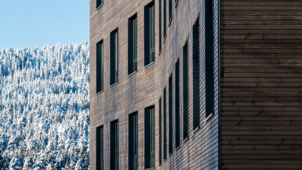 Fasade i tre med snekledt skog i bakgrunnen
