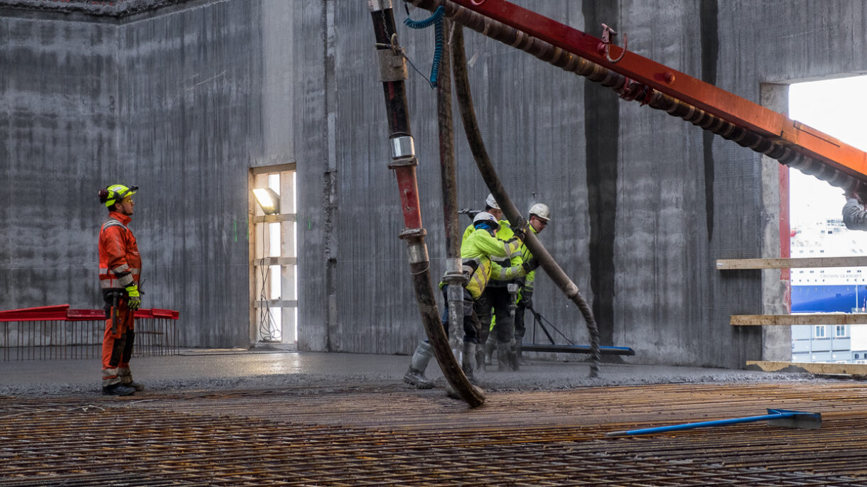 Støping av betong på byggeplass. Bygningsarbeidere. Foto