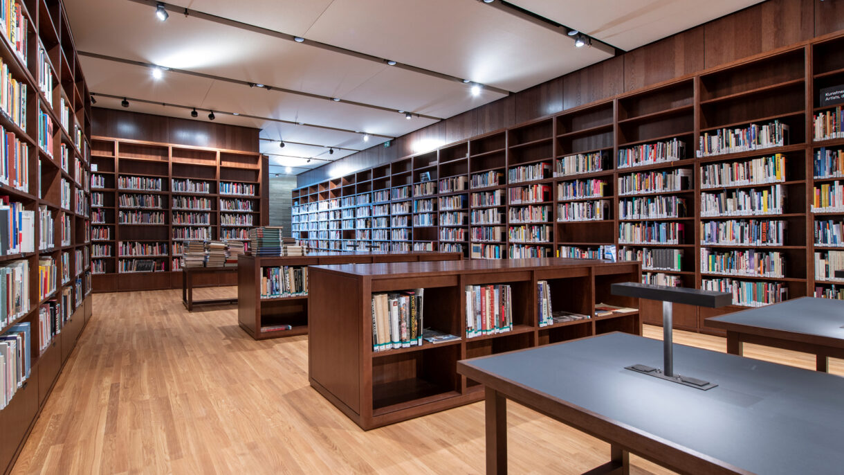 Biblioteksinteriør. Bøker. Hyller i mørkt tre.