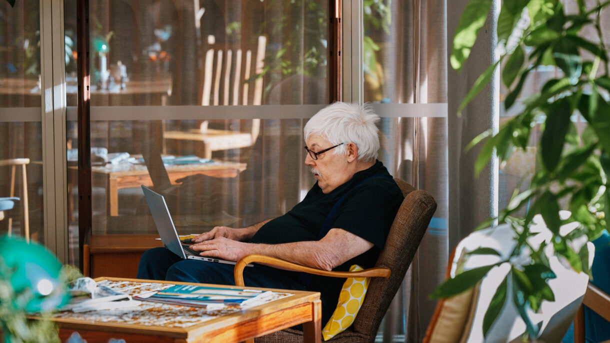 Mann som sitter på Romsås kulturhus og jobber på pc.