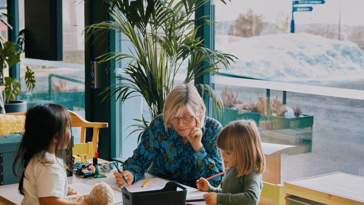 Leksehjelp på Romsås kulturhus. Kvinne og to barn rundt et bord.