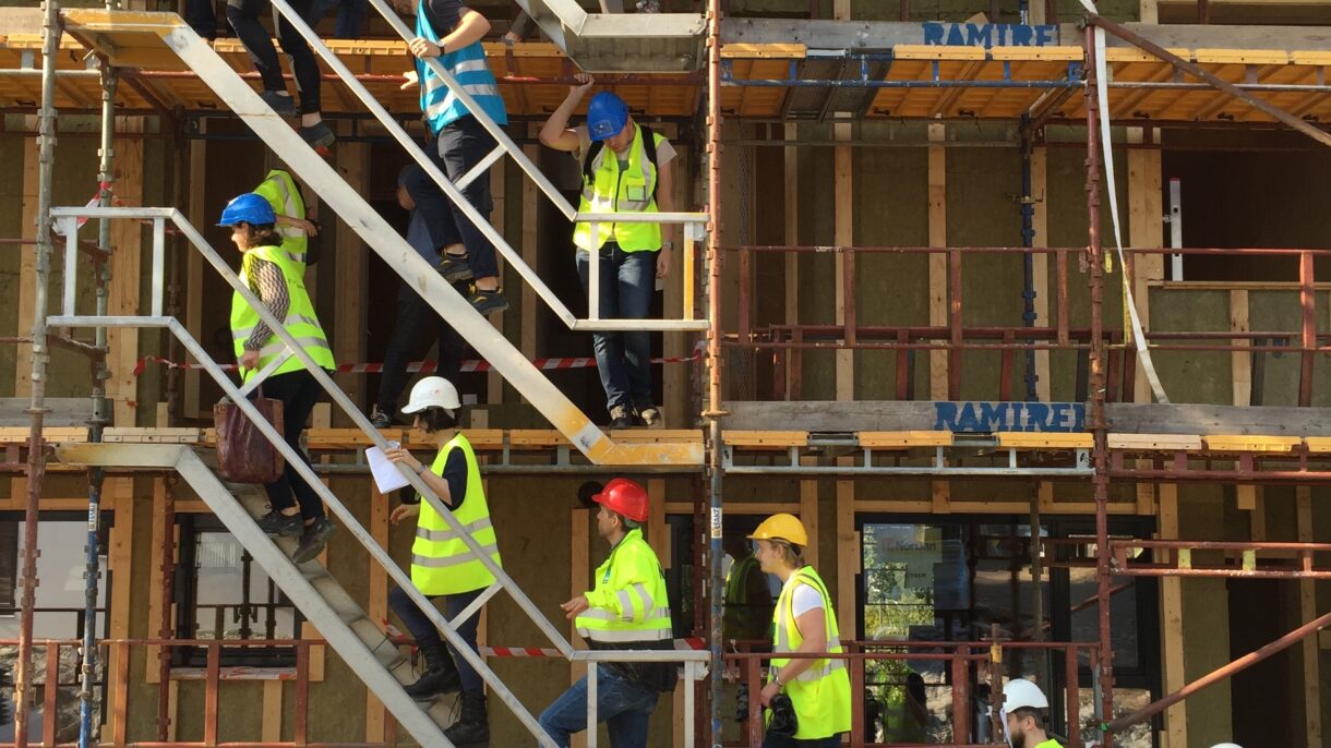 Personer besøker byggeplassen mens bygget reises. Foto