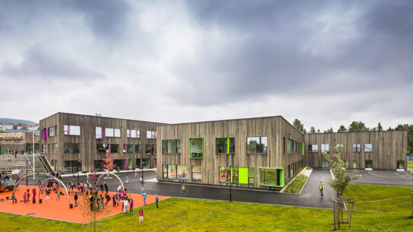 Skolegård. Skolebygg. Plen. Lekeapparat og barn. Foto