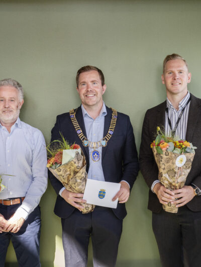 Fem personer totalt – tre med blomsterbukett og en med ordførerkjede. Foto.