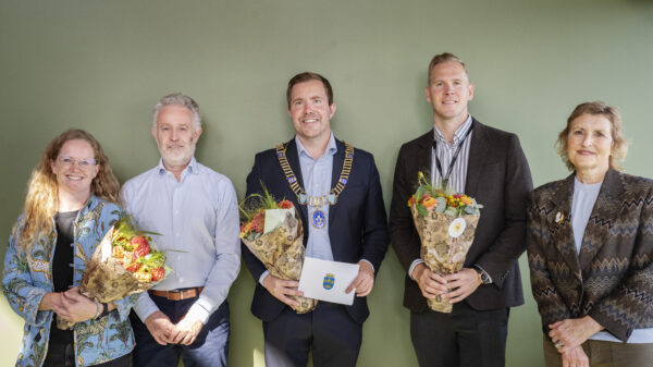 Fem personer totalt – tre med blomsterbukett og en med ordførerkjede. Foto.