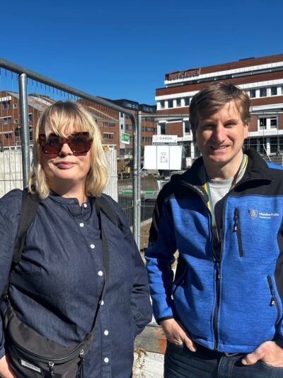 Kvinne og mann utenfor byggeplass. Foto.