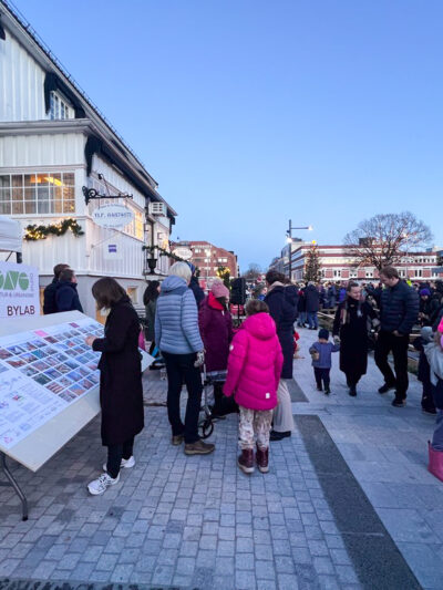 Plakatutstilling i gate med masse mennesker og ballonger. Foto.