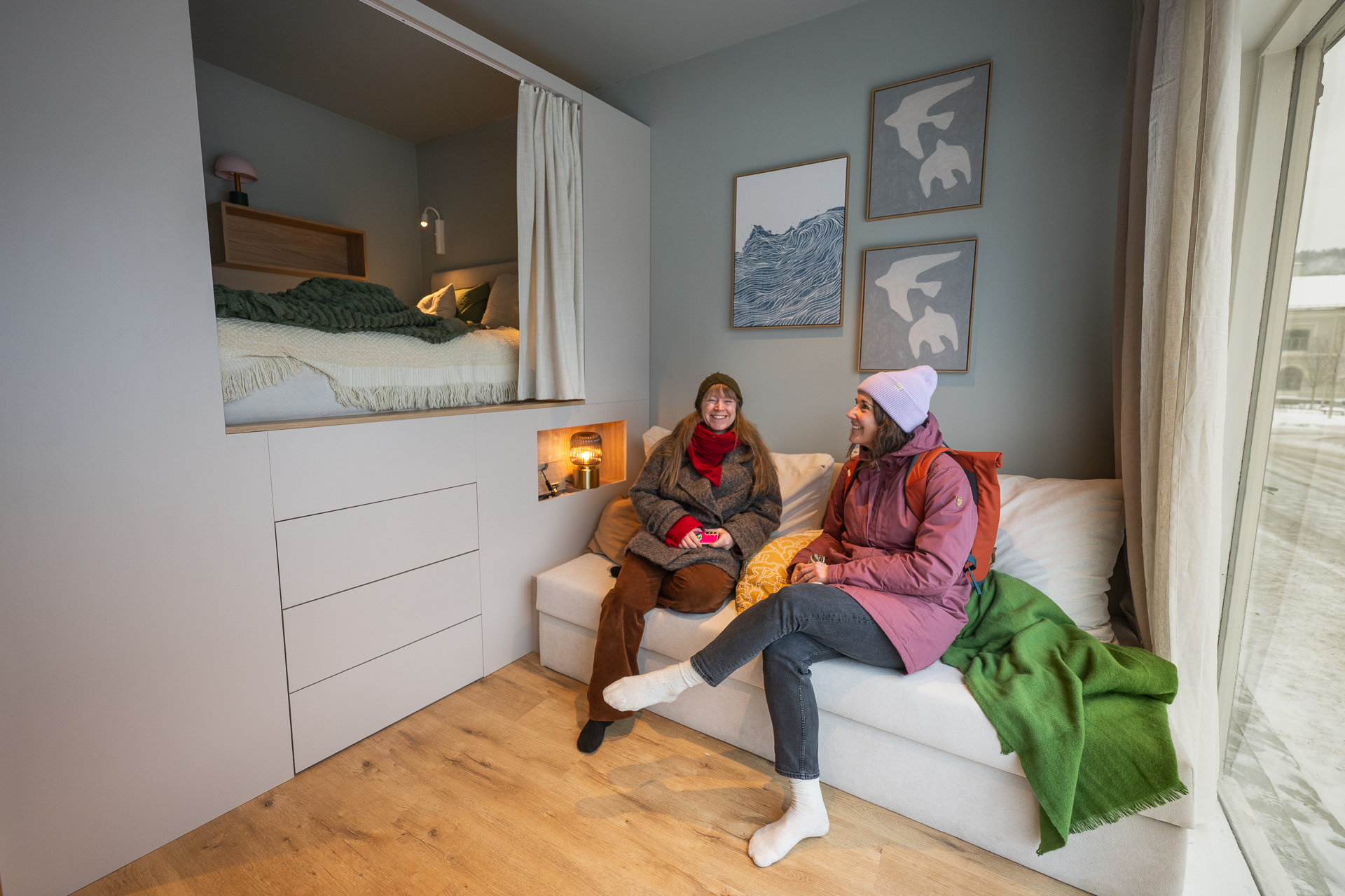 1:1 modell av en kompakt-leilighet. To personer tester stuen. Foto.