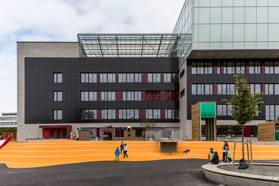 Fasade og skoleplass med barn. Foto