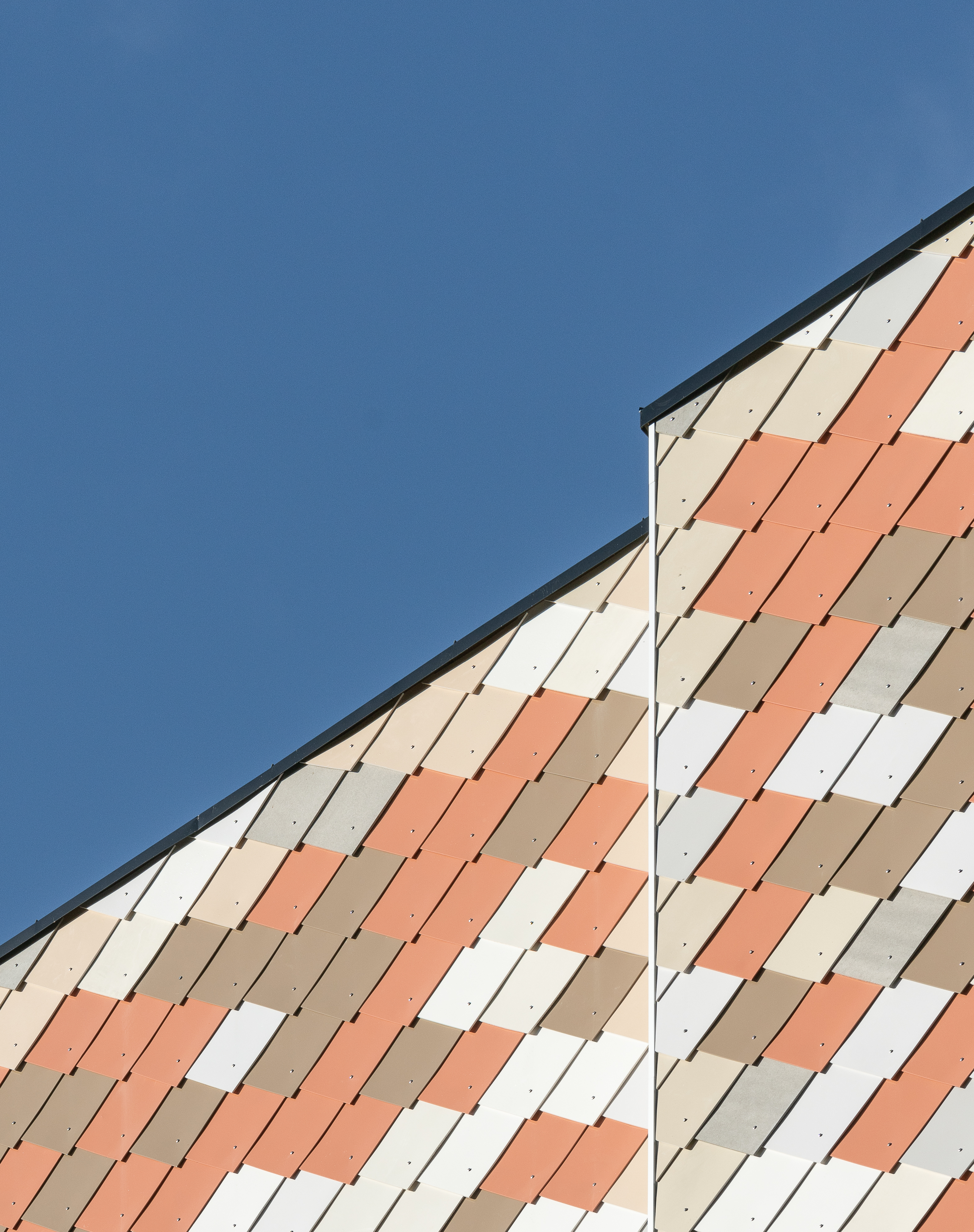 Detalj av fasade med mosaikk av ombrukte plater i ulike farger. Foto