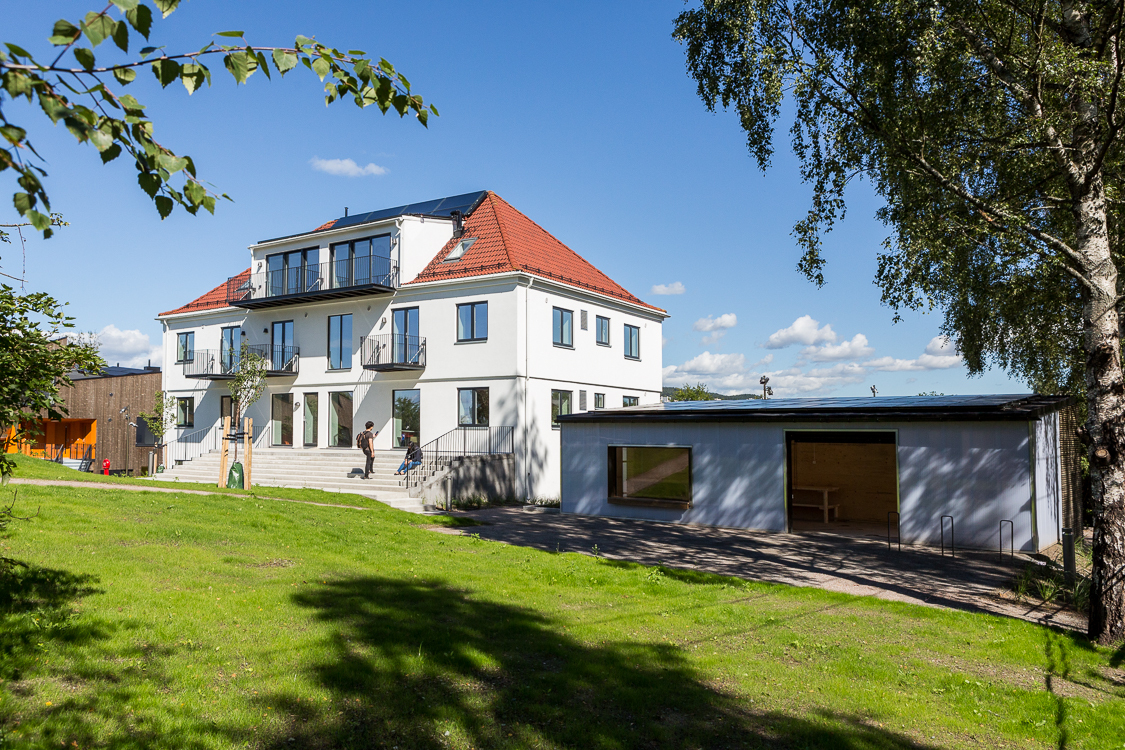 eldre bygg som er hvitmalt og rehabilitert. Sykkelmekkebod i forgrunnen. Foto